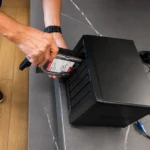 Person inserts an 8TB hard drive into a Synology NAS drive bay on a dark black enclosure.